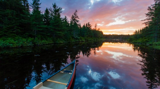 A canoe at sunrise on Little Berry Pond in Maine's Northern Forest. Cold Stream watershed, Johnson Mountain Township.